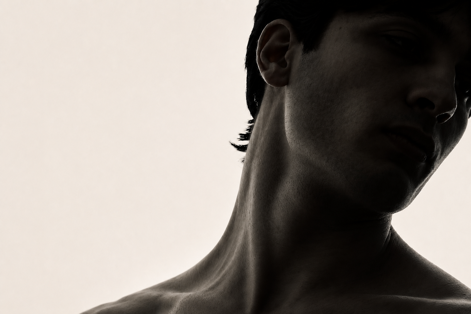 High-contrast black and white portrait of a man's neck and jawline