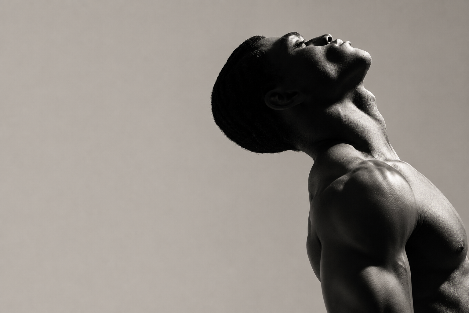 Black and white photograph of a muscular man looking upward in profile
